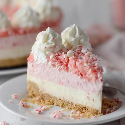 A piece of cake topped with white frosting and bright red cookie crunch.