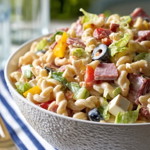 A big bowl packed with pasta salad and fresh meats and veggies.
