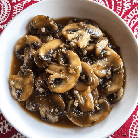 A bowl of mushrooms with gravy.