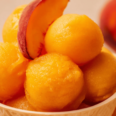 Bowl holding fresh peaches and plums.