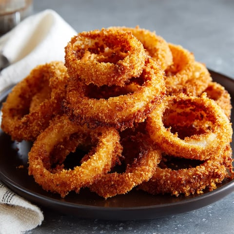 Crispy onion rings stacked on a plate.