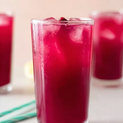 Chilled red fruity drink in a glass packed with ice.