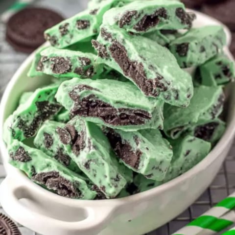 A bowl with chocolate pieces and green treats.