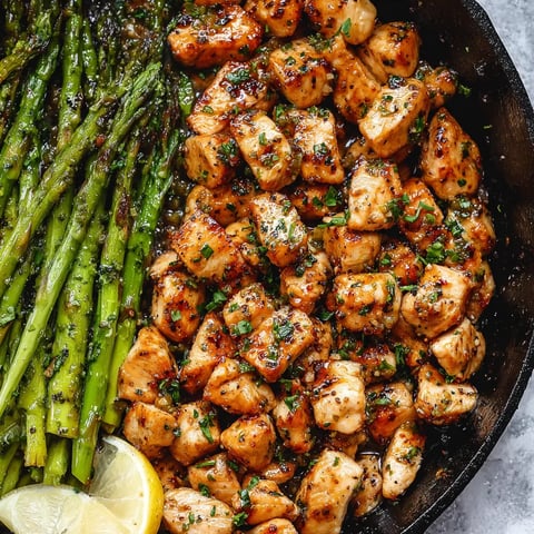 A skillet with chicken topped with a wedge of lemon.