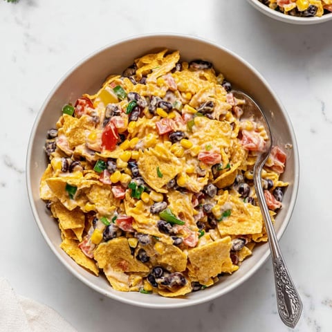 A bowl of nachos with beans and tomatoes.
