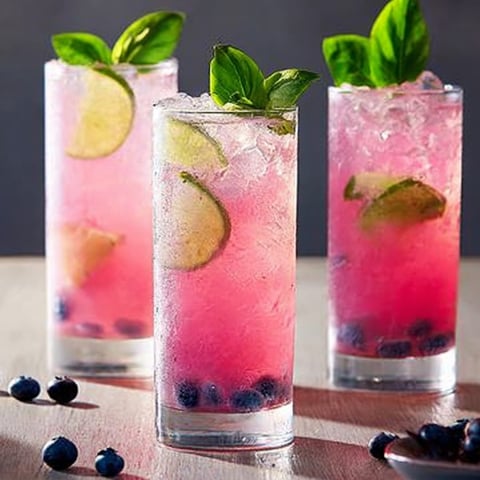 Three glasses of pink drink with blueberries.