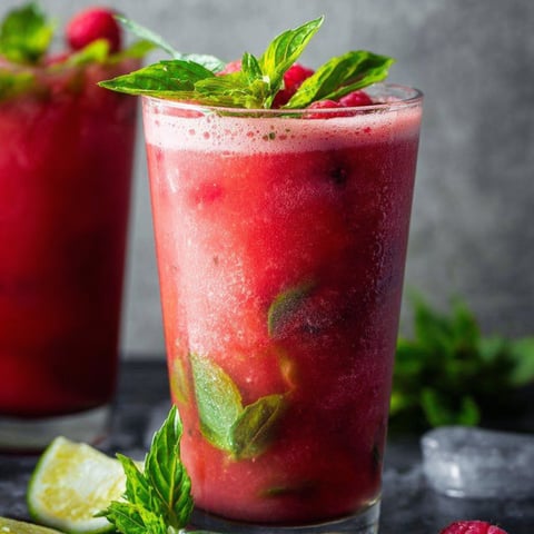 A glass of red juice with mint leaves.