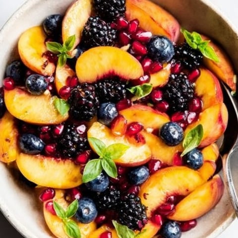 A bowl of fruit with blueberries, peaches, and blackberries.