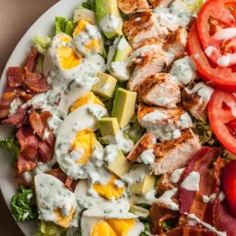 A plate of food with chicken, avocado, tomato, and bacon.