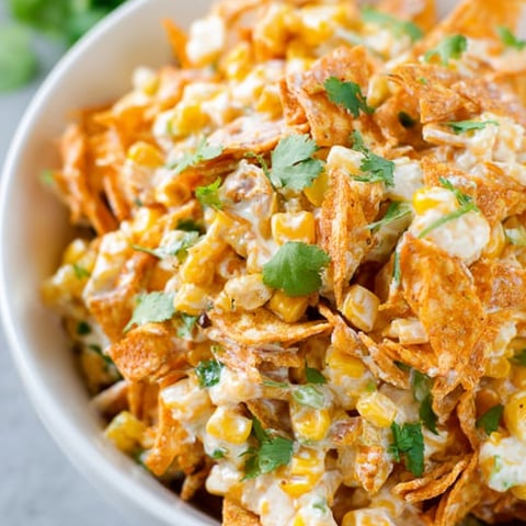 A bowl of corn chips with green onions.