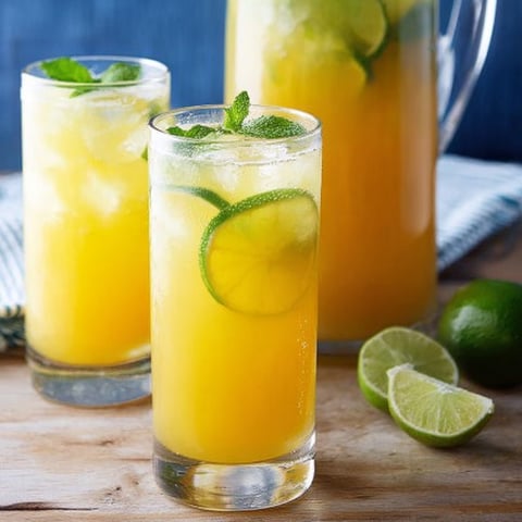 Two glasses of orange juice with limes.