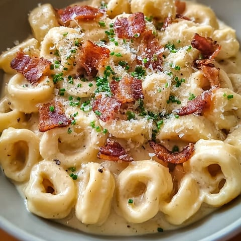 A bowl of pasta with bacon and cheese.
