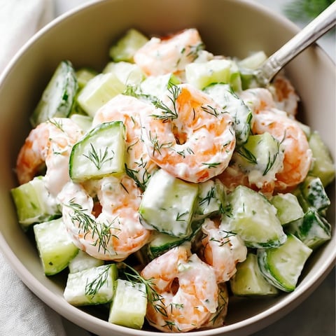 A bowl of shrimp salad with cucumbers.