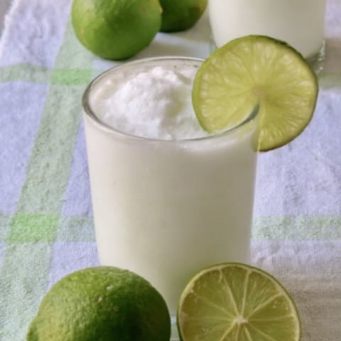 A glass of milk with limes on top.
