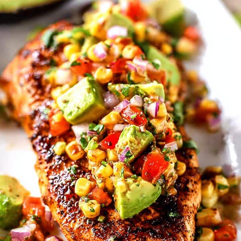 A plate of food with chicken, corn, and avocado.