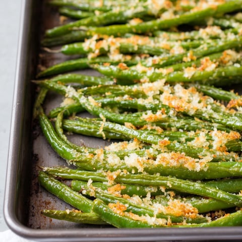 A pan of green beans with cheese on top.
