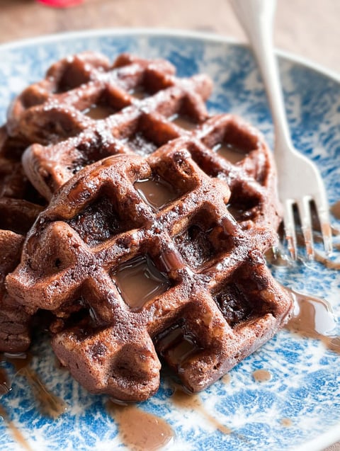 A plate of brownies with syrup on top.