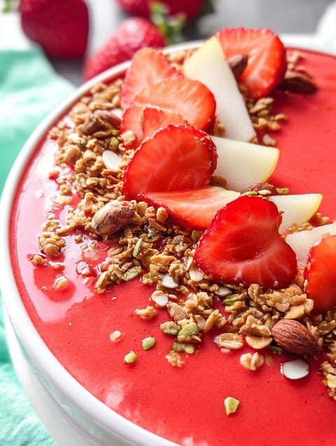 A bowl of strawberry smoothie with toppings.