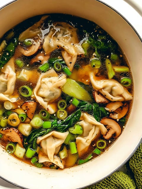 A bowl of soup with mushrooms, spinach, and other vegetables.