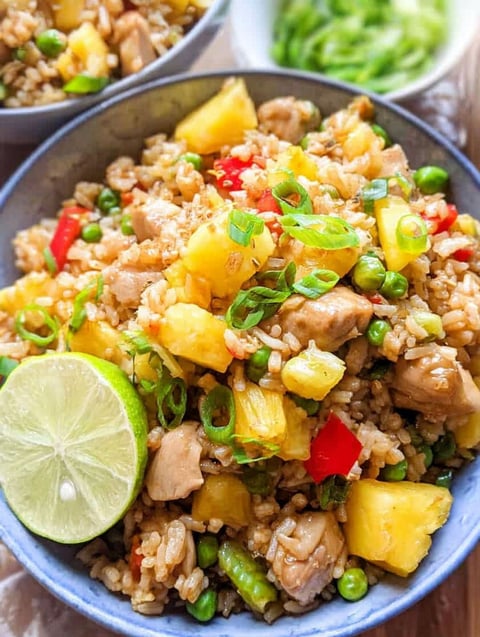 A bowl of rice with chicken and pineapple.