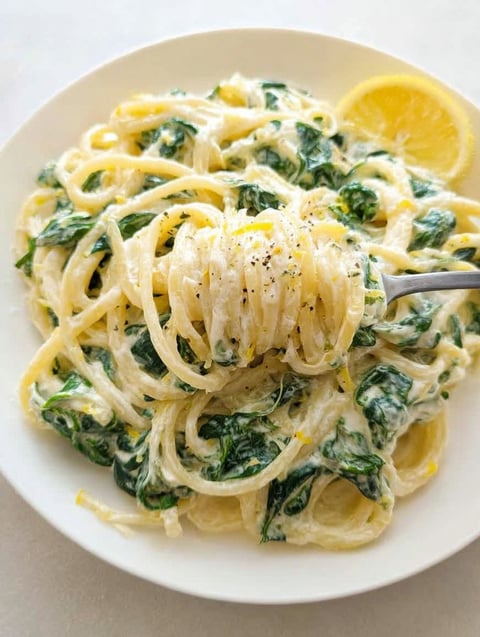 A plate of pasta with spinach and lemon.