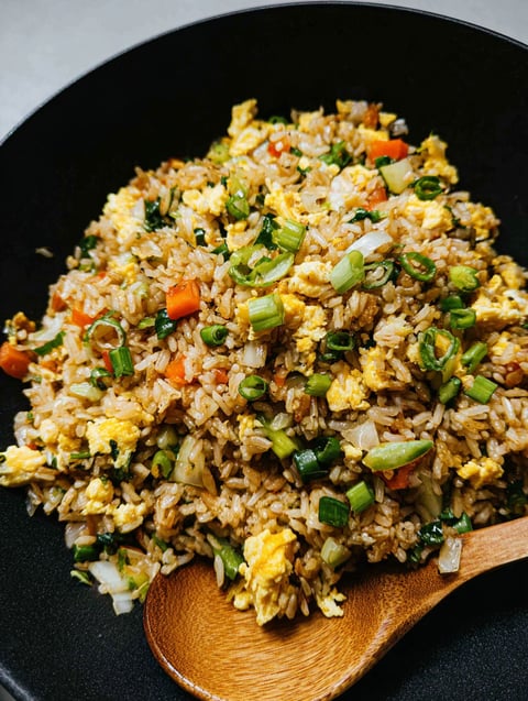 A plate of rice with vegetables and eggs.