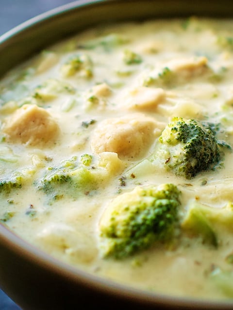 A bowl of soup with broccoli and chicken.