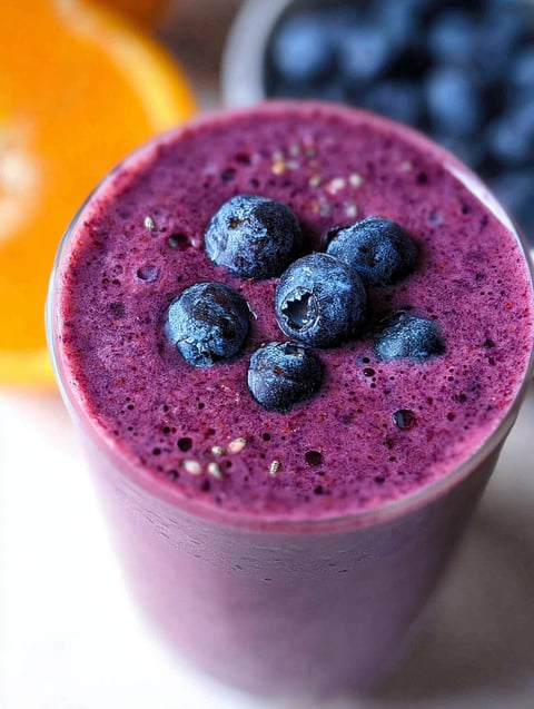 A glass of blueberry smoothie with a blueberry in it.