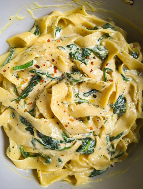 A bowl of pasta with spinach and garlic butter.