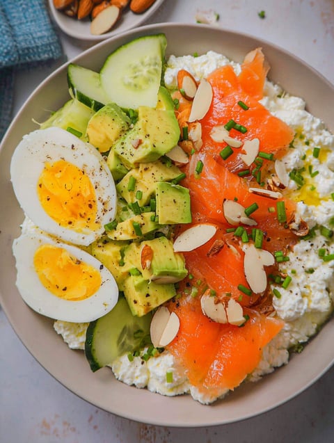 A bowl of food with eggs, avocado, and salmon.