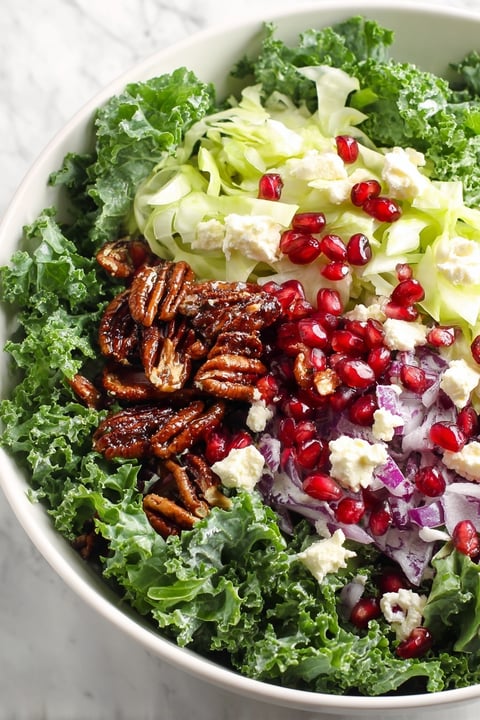 A bowl of salad with pomegranate seeds and cheese.