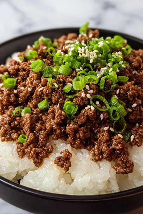 A bowl of beef with green onions.