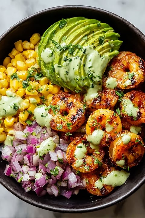 A bowl of food with grilled shrimp, avocado, corn salsa, and onions.