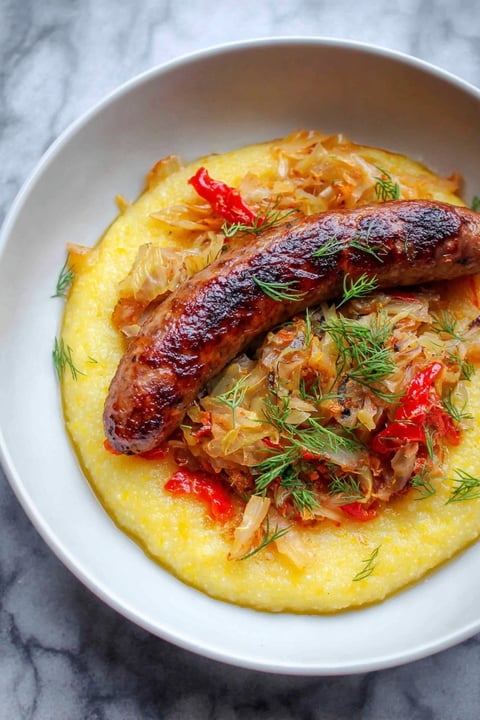 A plate of food with a sausage and cabbage.