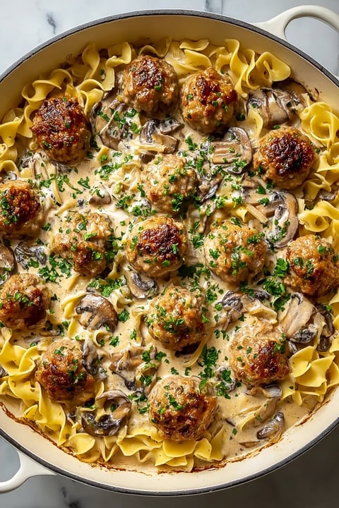 A dish of meatballs covered in mushrooms and sauce.