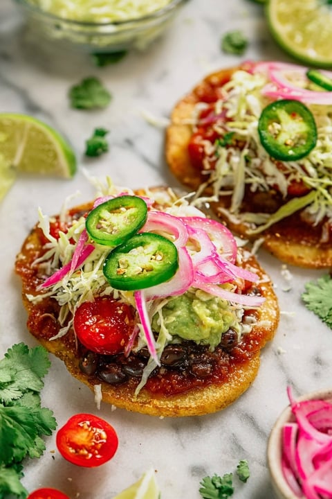 Two Mexican tlacoyos with toppings.