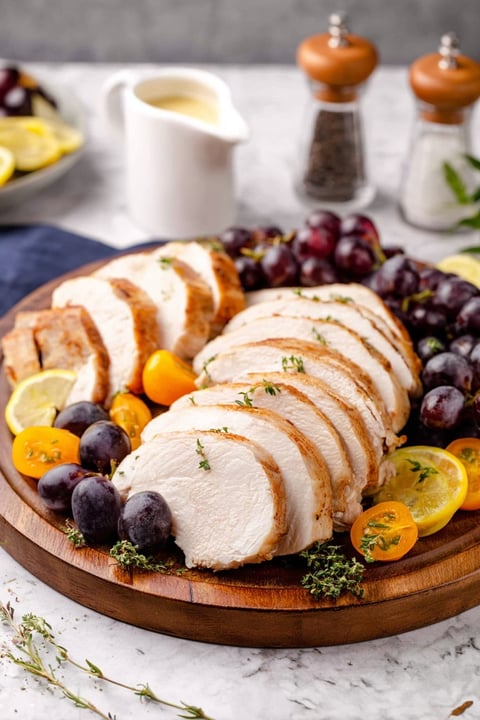 A plate of food with chicken, grapes, and lemon.