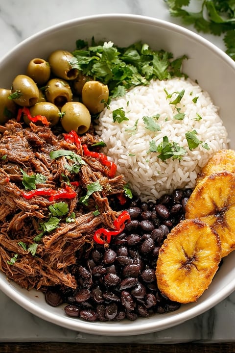 A bowl of Cuban Ropa Vieja with rice and beans.