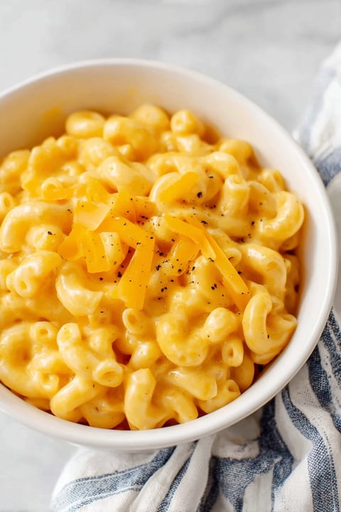A bowl of mac and cheese with a piece of cheese on top.