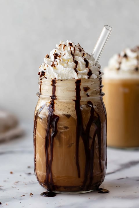 A glass of iced mocha coffee with whipped cream.